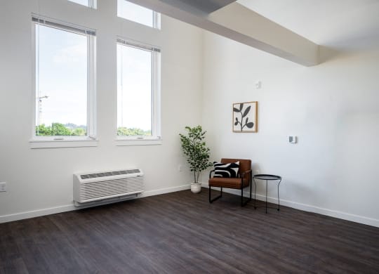 a living room with a chair, large windows and high ceilings
