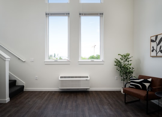 a living room with large windows, air conditioner, and stairs to loft space