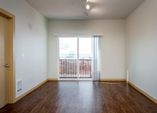 an empty living room with wood flooring and a large window