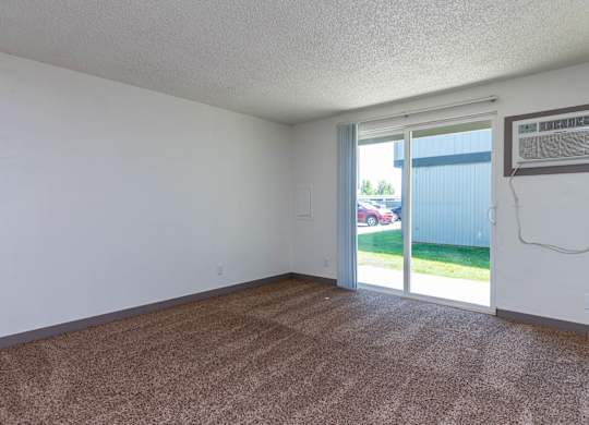 A room with a carpeted floor and a sliding glass door leading to a backyard.