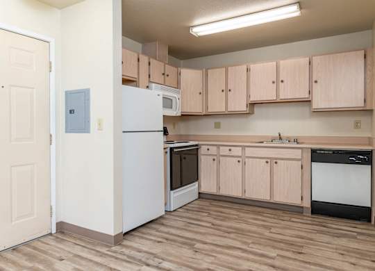 A kitchen with wooden floors and a white refrigerator.