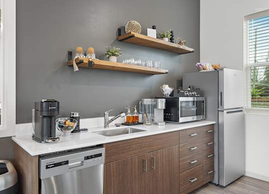 A modern kitchen with a grey wall and wooden shelves.