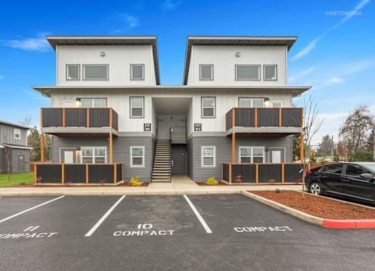 A two-story building with a parking lot in front.