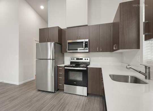 A modern kitchen with a stainless steel refrigerator, microwave, oven, and sink.