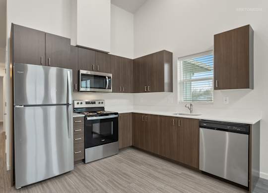 A modern kitchen with a stainless steel refrigerator, microwave, oven, and dishwasher.