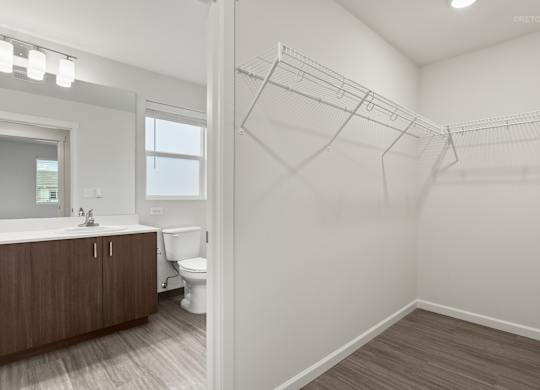 A white bathroom with a toilet, sink, and a walk-in closet.