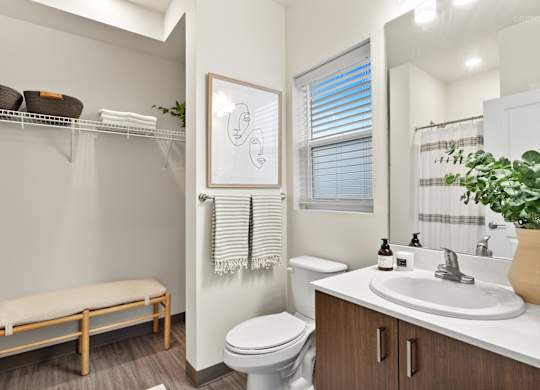 A bathroom with a toilet, sink, and a window with blinds.