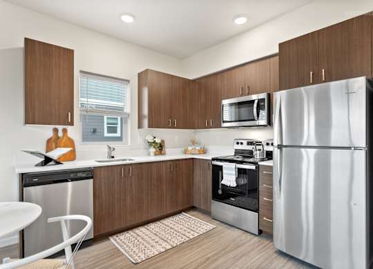 A modern kitchen with a refrigerator, microwave, oven, and sink.