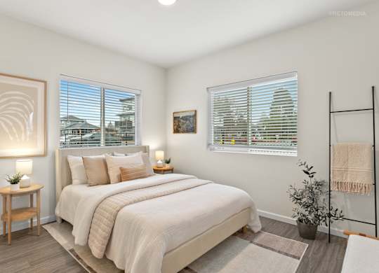 A bedroom with a large bed, a wooden nightstand, and a framed picture on the wall.