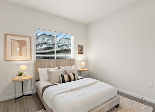 A bedroom with a large bed and a window with blinds.