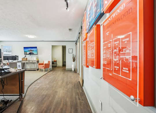 A room with a desk and a computer, a chair and a poster on the wall.