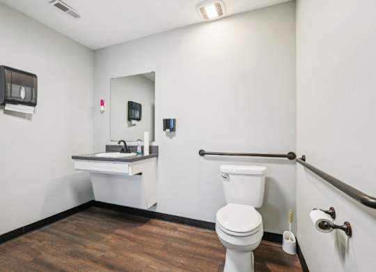 A white toilet sits in a bathroom with a sink and mirror.