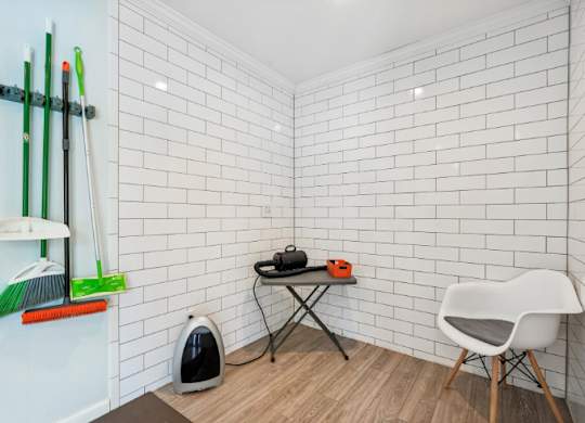 A white chair is placed in front of a white tiled wall.