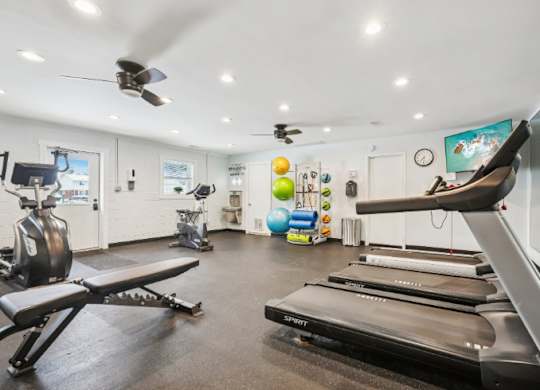 A gym with treadmills, exercise equipment, and a fan.