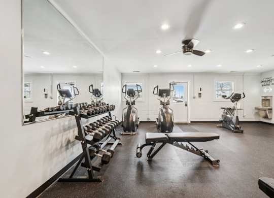 A gym with a variety of equipment including weights and a bench.
