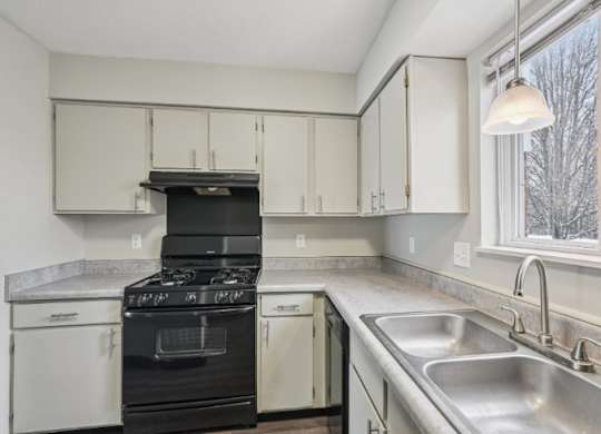 A kitchen with a black stove top oven and white cabinets.
