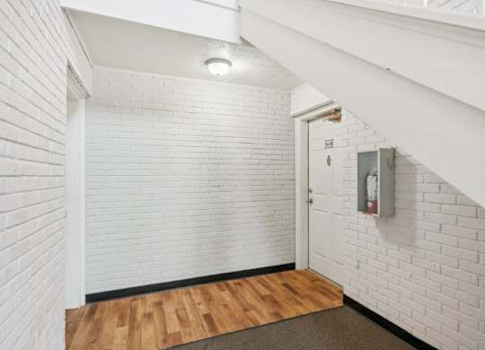 A white brick wall with a door and a fire extinguisher mounted on it.