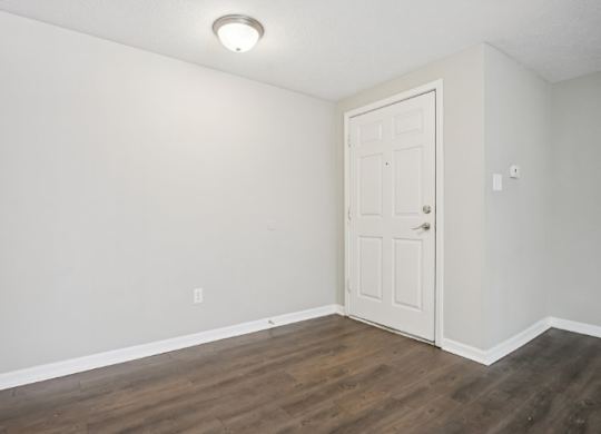 A room with a white door and wooden floor.