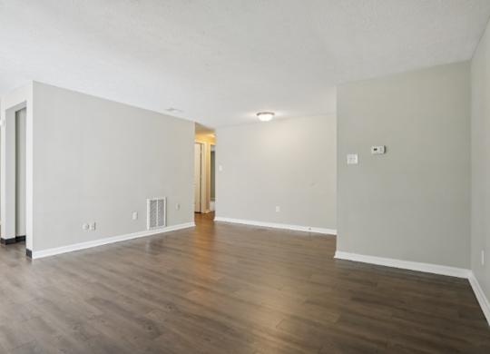 A large empty room with wooden floors and white walls.