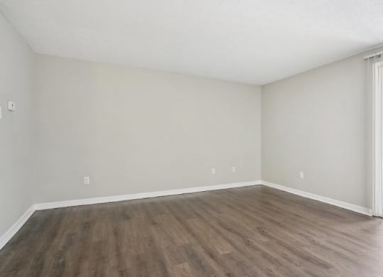 A room with wooden flooring and a window with bars on it.