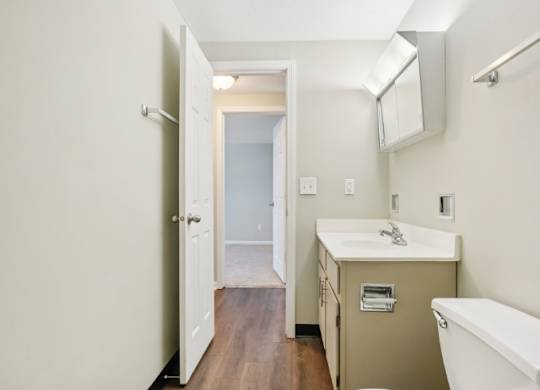 A bathroom with a white tub, sink, and wooden floor.