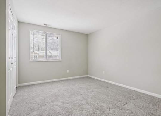 A room with a carpeted floor and a window.