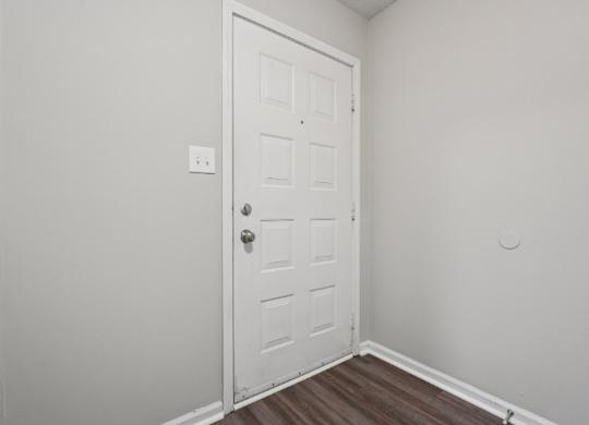 A white door with a silver handle is in a room with white walls.