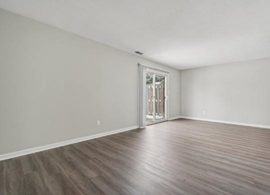 A room with a wooden floor and a door leading to a balcony.