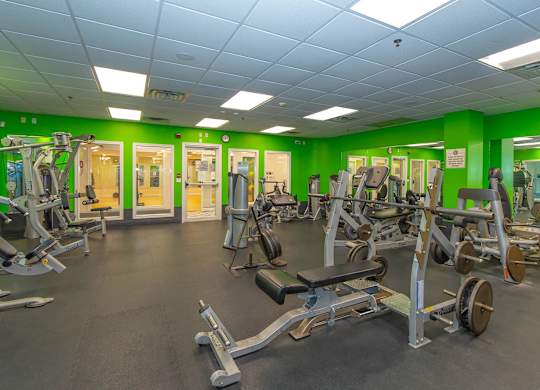 A gym with a variety of equipment including treadmills, weights, and exercise machines.