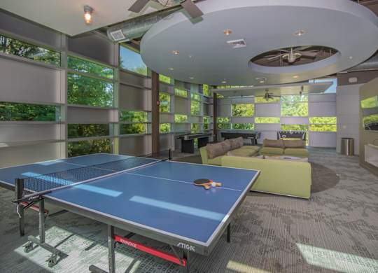 A ping pong table is in the middle of a room with a ceiling fan.
