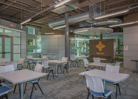 A conference room with tables and chairs and a sign that says bloom.