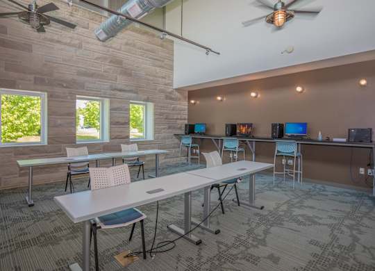 A room with tables and chairs and a ceiling fan.