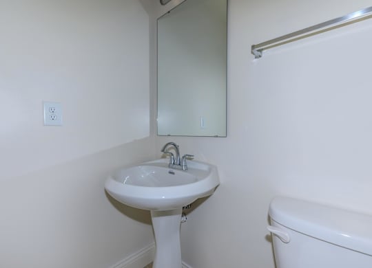 A white pedestal sink with a mirror above it.