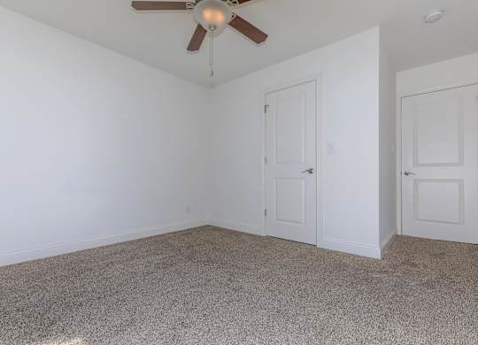 A room with a ceiling fan and carpeted floor.