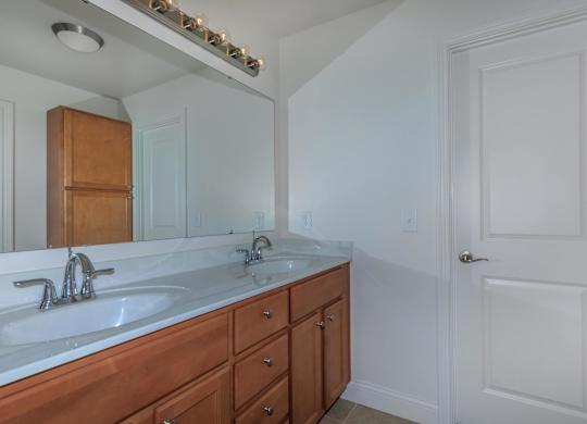 A bathroom with a white sink and a wooden vanity.