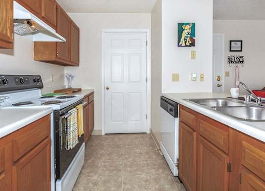 A kitchen with a white door and brown cabinets.