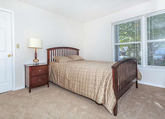 A bedroom with a bed, nightstand, and window.