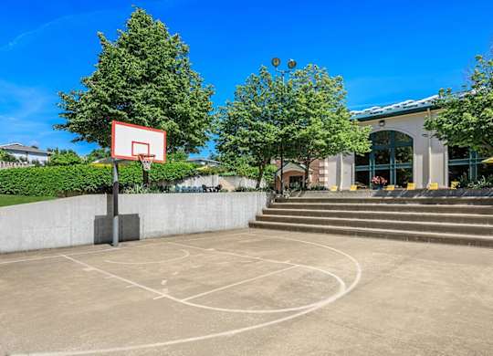 A basketball court with a hoop and a building in the background.