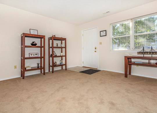A room with a carpeted floor and a window with blinds.