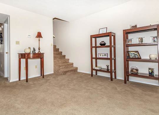 A room with a carpeted floor and a staircase.