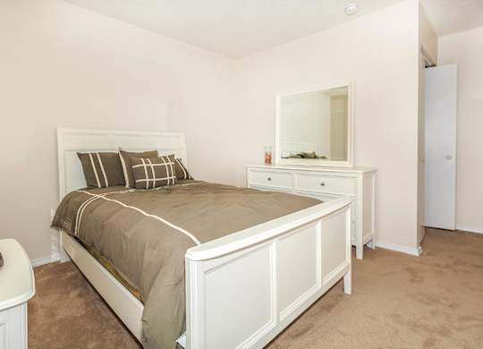 A bedroom with a bed, dresser, and mirror.