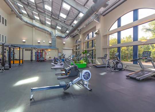 A gym with a variety of equipment including treadmills, weights, and exercise machines.