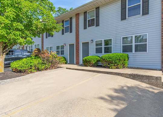 A residential building with a parking lot in front.