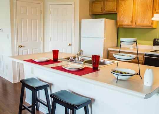 A kitchen with a white fridge and a red tablecloth on the counter.
