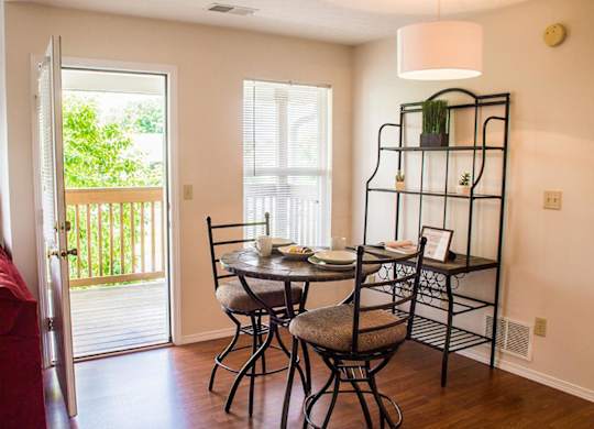A dining room with a table set for two and a red couch.