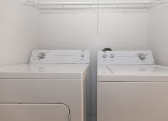 Two white washing machines in a small laundry room.
