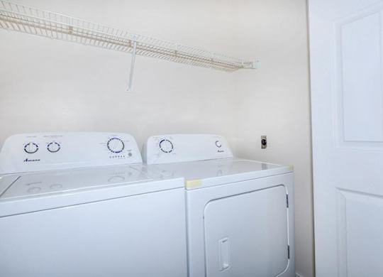 Two white front loading washing machines in a laundry room.