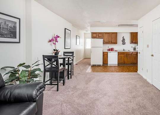 A black leather chair sits in a living room with a dining table and chairs.