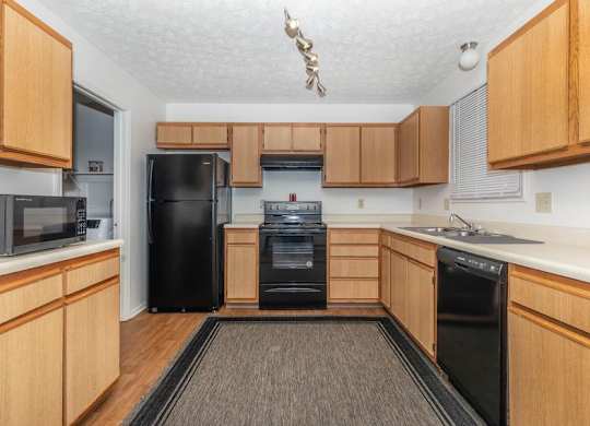 A kitchen with wooden cabinets and black appliances.