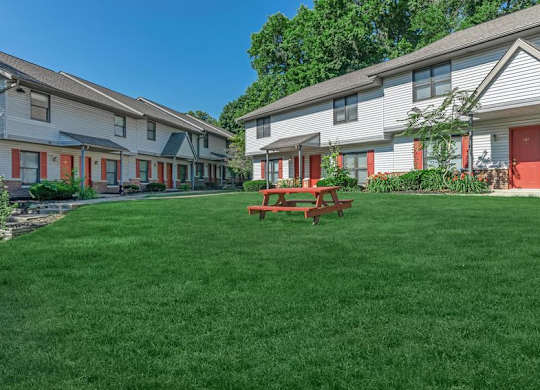 A grassy area in front of a building with a picnic table.